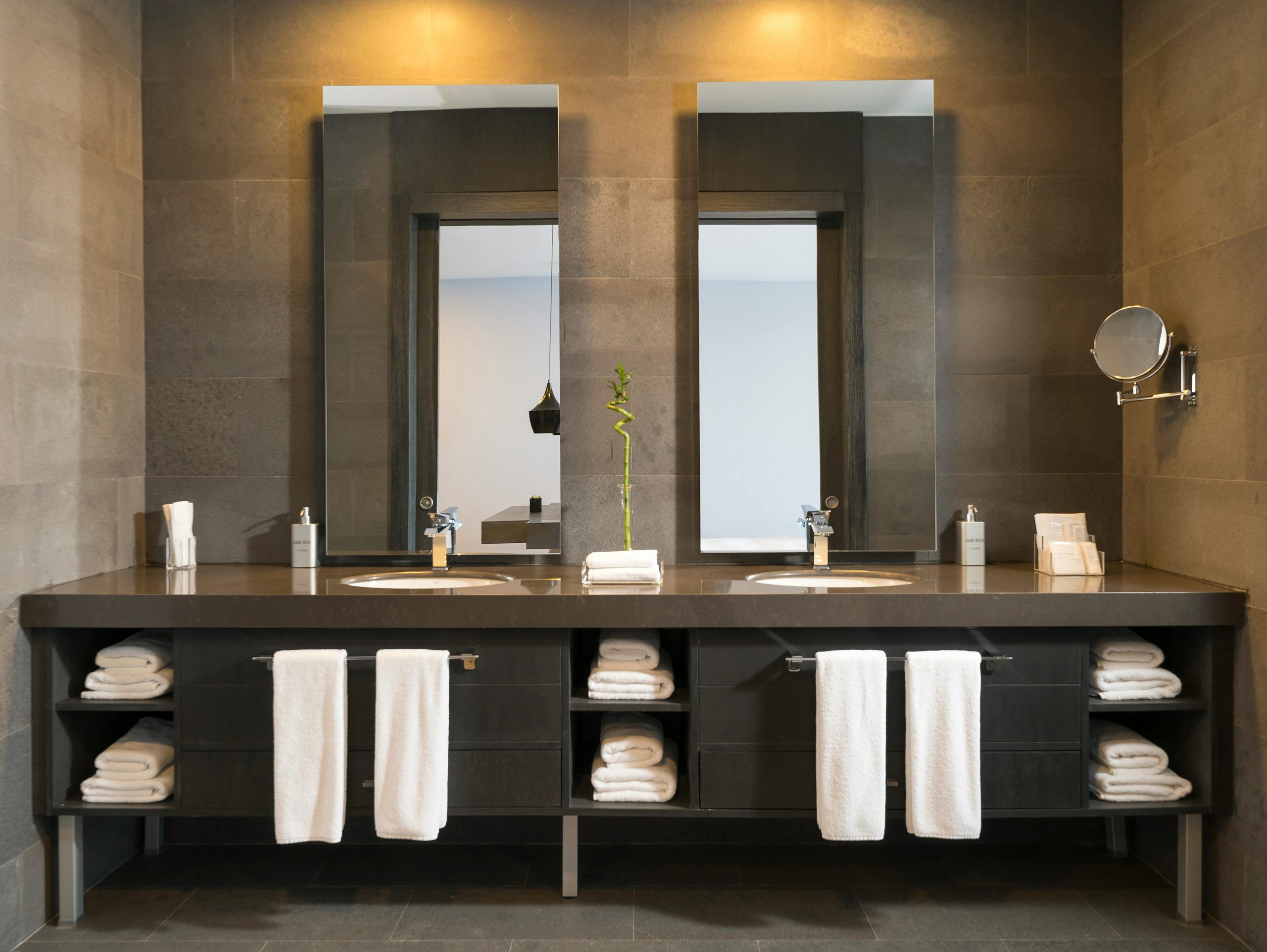 Home Stylish modern bathroom interior with twin mirrors and towels arranged over sleek dark countertops.
